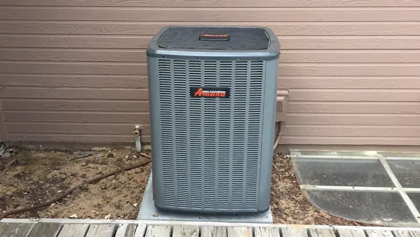 Outdoor air conditioner condenser unit on a concrete pad beside a house